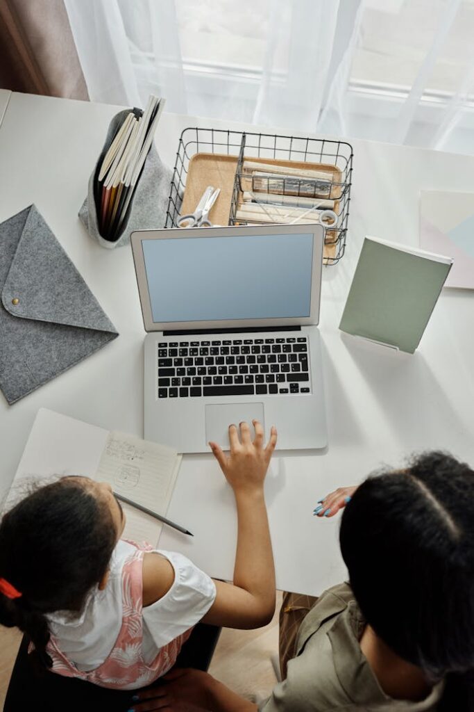 Kind wird am Laptop unterstützt bei den Aufgaben