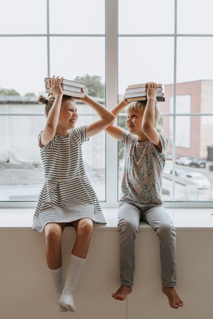 Zwei lachende Kinder balancieren Bücher auf ihren Köpfen