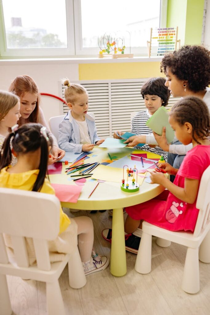 Kinder basteln mit einer Betreuerin am Tisch